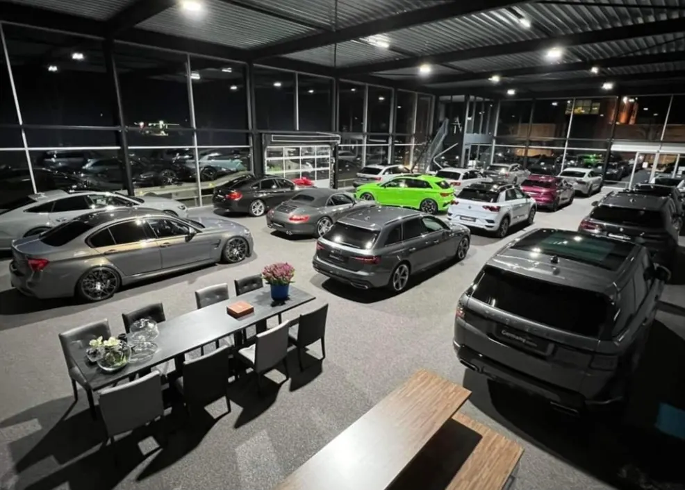 De showroom van Germany Dealer bij avond, met premium occasions en de lange tafel